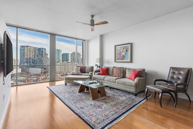 living room with a view of city, ceiling fan, expansive windows, and wood finished floors