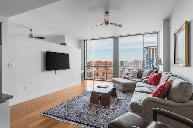 living room featuring ceiling fan, floor to ceiling windows, wood finished floors, and baseboards