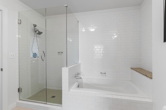 bathroom featuring a stall shower and a bath