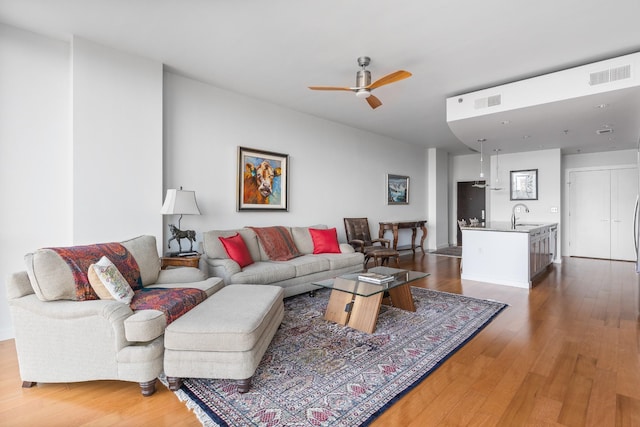 living area featuring a ceiling fan, visible vents, and dark wood-style flooring