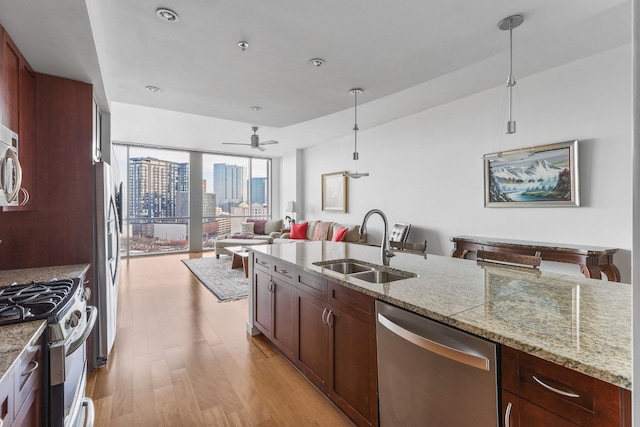 kitchen featuring a view of city, pendant lighting, appliances with stainless steel finishes, open floor plan, and a sink