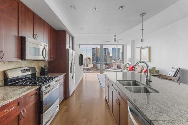 kitchen featuring appliances with stainless steel finishes, a city view, a sink, and light stone counters