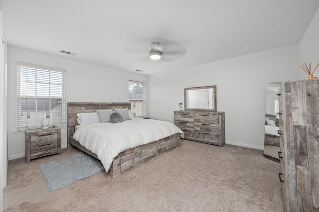 bedroom with baseboards, a ceiling fan, visible vents, and light colored carpet