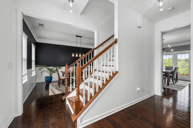 staircase with baseboards, wood finished floors, visible vents, and a notable chandelier