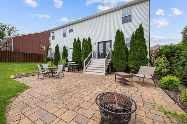 rear view of property with a fire pit, french doors, a patio, a yard, and outdoor dining space