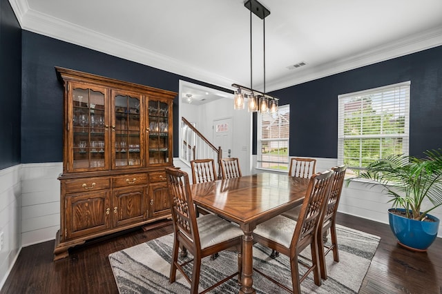 dining space with dark wood-type flooring, a wainscoted wall, visible vents, and stairs