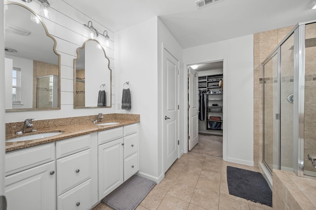 full bathroom with tile patterned flooring, a shower stall, a spacious closet, and a sink