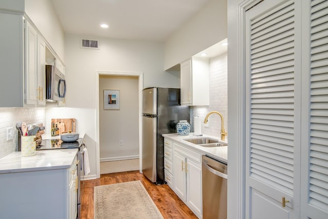 kitchen featuring stainless steel appliances, a sink, white cabinetry, visible vents, and light countertops