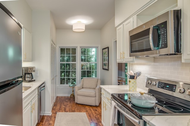 kitchen with white cabinets, light wood-style floors, stainless steel appliances, and backsplash