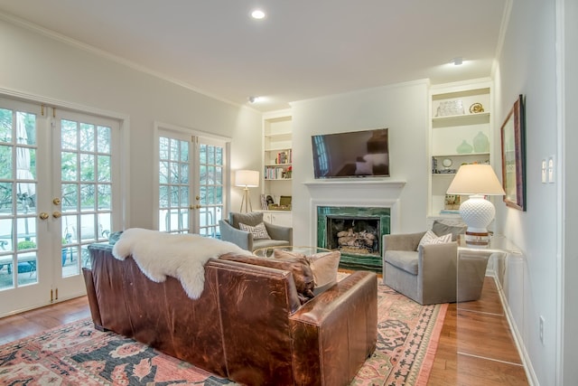 living room featuring built in shelves, french doors, plenty of natural light, and light wood-style flooring