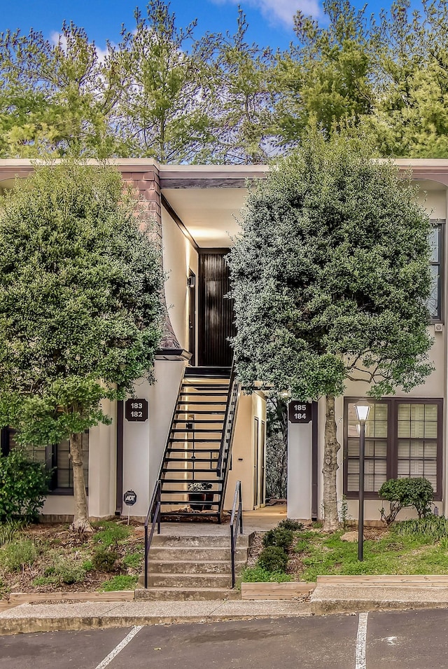 view of exterior entry with uncovered parking and stucco siding