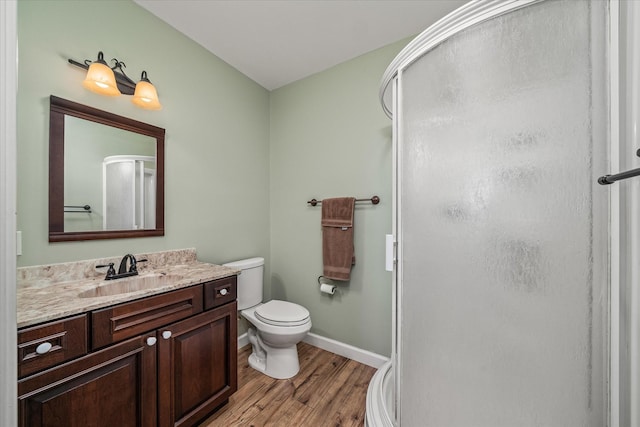 full bath with a stall shower, baseboards, toilet, wood finished floors, and vanity