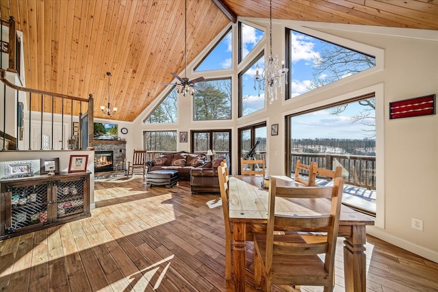 interior space with vaulted ceiling with beams, a stone fireplace, ceiling fan with notable chandelier, and wooden ceiling