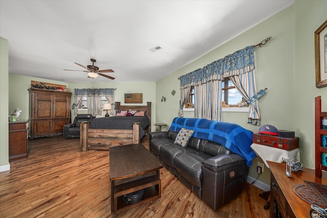 living area with visible vents, ceiling fan, baseboards, and wood finished floors