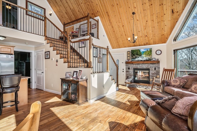 living room featuring baseboards, wood ceiling, stairs, light wood-type flooring, and a fireplace