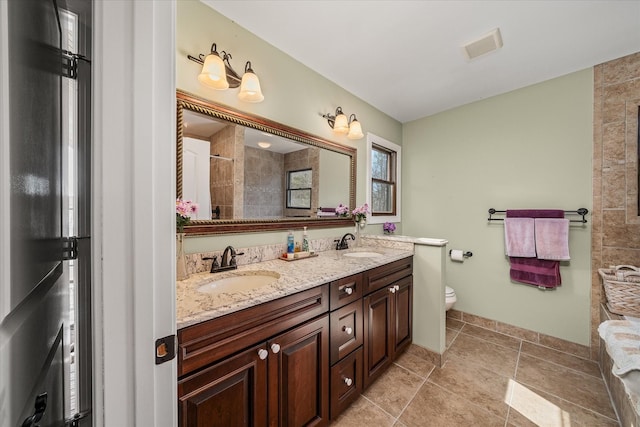 bathroom with double vanity, visible vents, toilet, and a sink