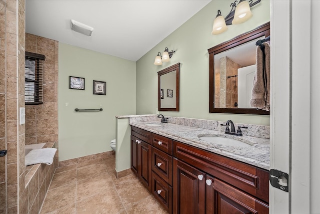 full bathroom with toilet, double vanity, a sink, and tile patterned floors