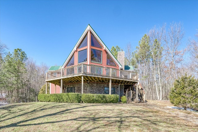 view of front of house with stone siding, a chimney, stairway, a deck, and a front lawn