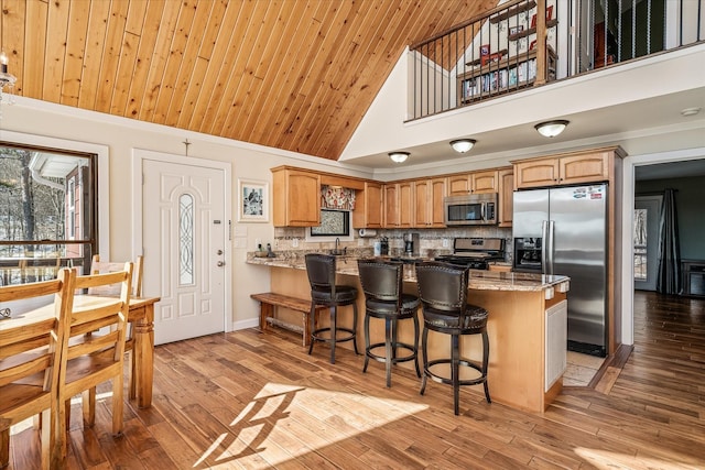 kitchen with backsplash, appliances with stainless steel finishes, light stone countertops, wooden ceiling, and a peninsula