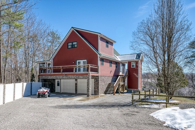 rustic home with driveway, stone siding, stairway, and fence