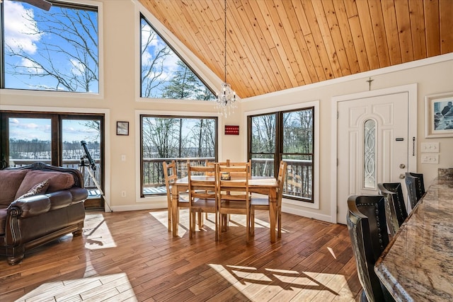 dining room with light wood finished floors, baseboards, wooden ceiling, high vaulted ceiling, and a notable chandelier