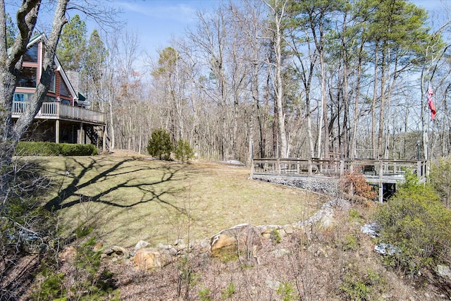 view of yard with a deck, stairs, and a view of trees