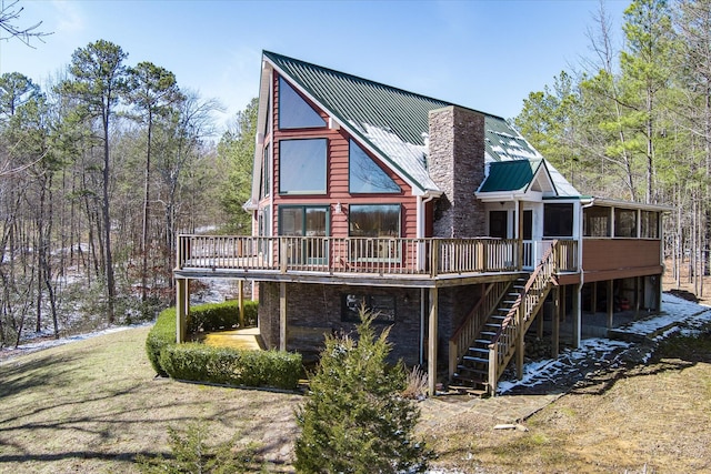 rear view of house featuring a sunroom, a chimney, metal roof, stairs, and a wooden deck