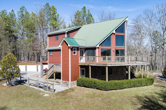 back of house featuring a yard, stairway, metal roof, stone siding, and a wooden deck