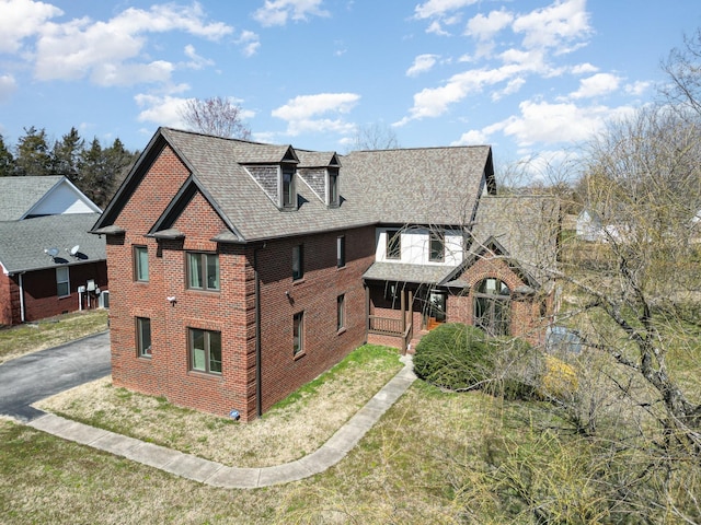 view of front of house featuring driveway, a front lawn, and brick siding