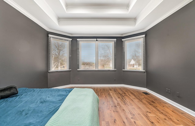 bedroom featuring multiple windows, a tray ceiling, and wood finished floors