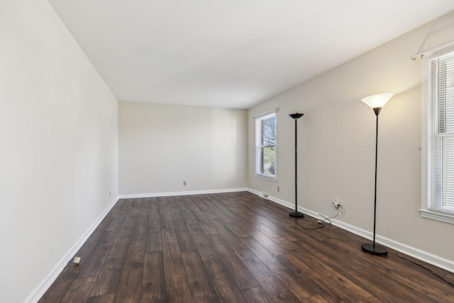 empty room with baseboards and dark wood-type flooring