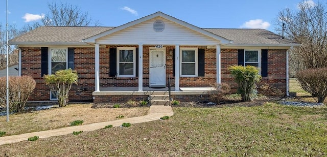 bungalow-style house with a shingled roof, a front yard, a porch, and brick siding