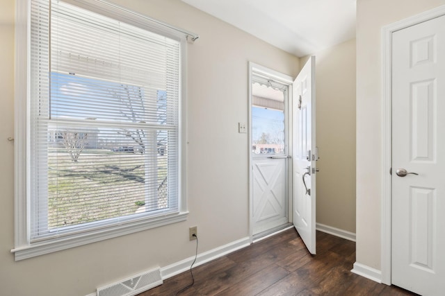 doorway to outside featuring dark wood finished floors, visible vents, and baseboards