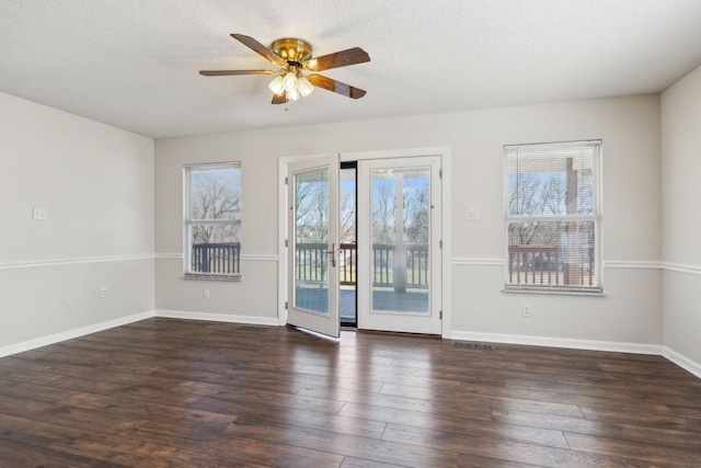 unfurnished room with plenty of natural light, dark wood finished floors, and baseboards