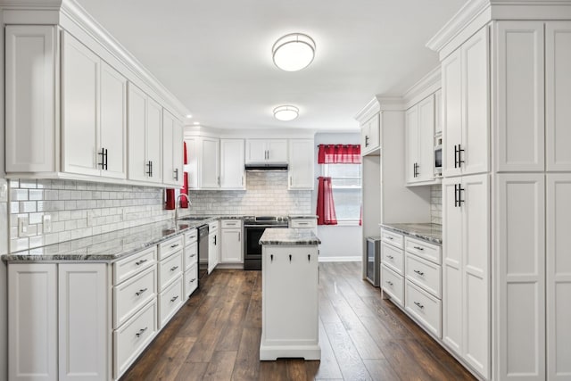 kitchen featuring white cabinets, stainless steel electric range oven, a kitchen island, light stone countertops, and a sink