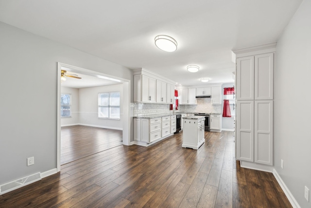 kitchen with dark wood-style floors, stainless steel electric range, visible vents, and white cabinets