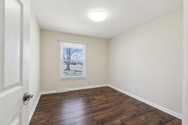 empty room featuring baseboards, visible vents, and dark wood-type flooring