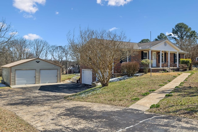 view of front of home with covered porch, brick siding, an outbuilding, and a garage