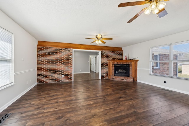 unfurnished living room with a textured ceiling, a fireplace, visible vents, and dark wood-style flooring