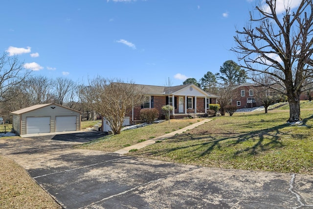 view of front of house with brick siding, a front yard, a detached garage, and an outdoor structure