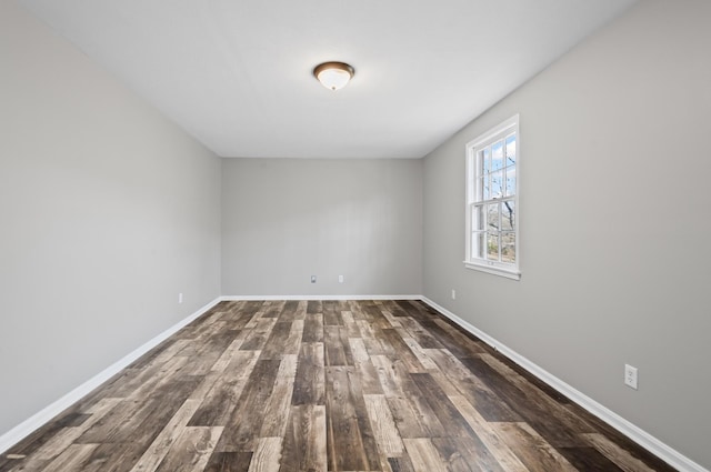 spare room featuring dark wood-style floors and baseboards