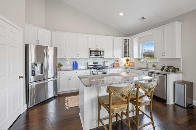 kitchen featuring a kitchen island, visible vents, white cabinets, appliances with stainless steel finishes, and glass insert cabinets