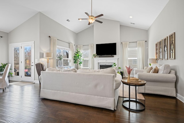 living area featuring a fireplace, visible vents, dark wood-type flooring, high vaulted ceiling, and baseboards