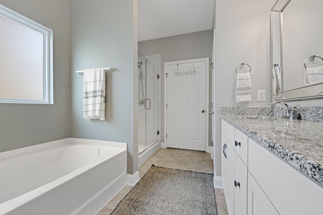 bathroom with baseboards, vanity, a shower stall, and a bath