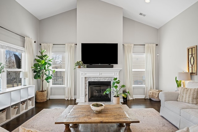 living room with vaulted ceiling, dark wood-style flooring, a fireplace, and visible vents