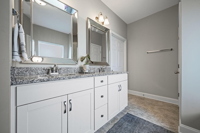 bathroom featuring double vanity, a sink, and baseboards