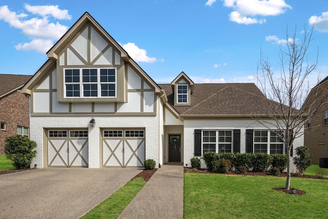 tudor home with brick siding, a shingled roof, a garage, driveway, and a front lawn