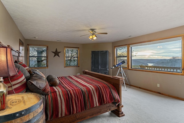 bedroom with light carpet, ceiling fan, a textured ceiling, and baseboards