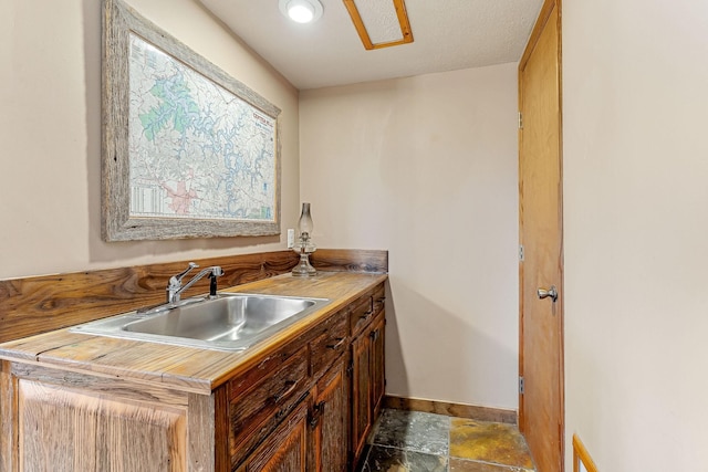 kitchen with light countertops, a sink, and baseboards