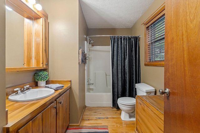 bathroom featuring toilet, shower / tub combo with curtain, wood finished floors, a textured ceiling, and vanity